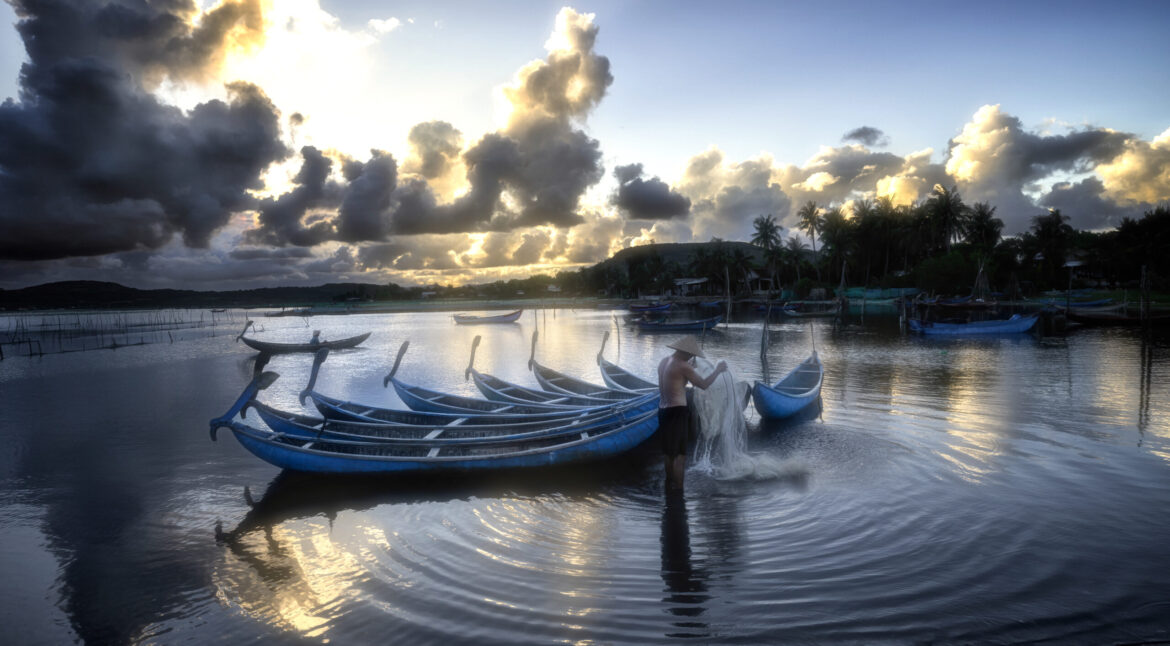 Tranquility scenery fisherman and small fishing boats at lagoon in Phu Yen Province in Vietnam.